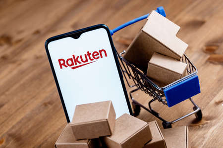 Kazan, Russia - Oct 12, 2021: Rakuten Group is Japanese electronic commerce and online retailing company. Smartphone with Rakuten on the screen, shopping cart and parcels.のeditorial素材