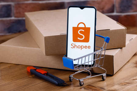 Kazan, Russia - Oct 14, 2021: Shopee is an e-commerce technology company. Smartphone with Shopee on the screen, shopping cart and parcels.のeditorial素材