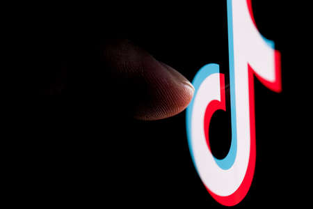 Kazan, Russia - Oct 31, 2021: The finger reaches for the TikTok social network logo on the smartphone screen.のeditorial素材