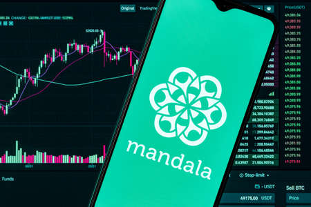 Kazan, Russia - Nov 06, 2021: Mandala is a cryptocurrency exchange. A smartphone with the Mandala exchange on the background of the live trading webpage. Mandala exchange dashboard.のeditorial素材