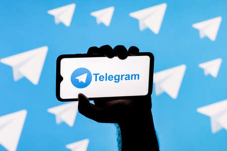 Kazan, Russia - Nov 11, 2021: Smartphone with the Telegram messenger on the screen in a clenched hand on the background of Telegramのeditorial素材