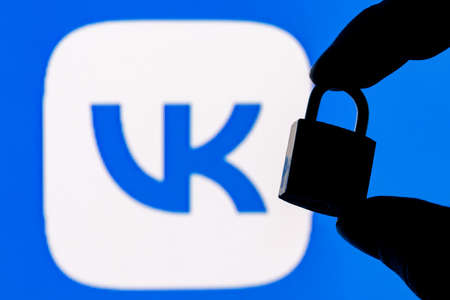 Kazan, Russia - Nov 13, 2021: Fingers hold a closed security lock on the background of the VKontakte...