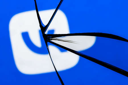Kazan, Russia - Nov 13, 2021: Logo of the VKontakte social network in the reflection of a broken mirror. The concept of problems in the work of VKontakte.のeditorial素材
