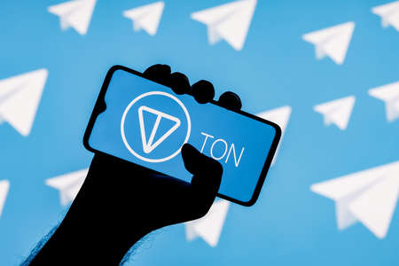 Kazan, Russia - Nov 14, 2021: The Open Network is a blockchain-based decentralized computer network technology. Smartphone with the TON logo on the screen in hand on the background of Telegram logos.のeditorial素材