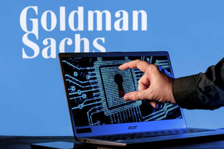 Kazan, Russia - Dec 20, 2021: Laptop with lock symbol on screen on background of Goldman Sachs bank logo. Finger points to lock symbol. Concept of data hacking.のeditorial素材