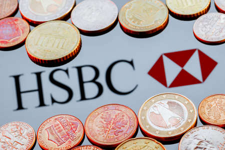 Kazan, Russia - Jan 16, 2022: Variety of metal coins on background of HSBC bank logoのeditorial素材