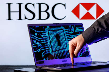 Kazan, Russia - Jan 16, 2022: Laptop with lock symbol on screen on background of HSBC bank logo. Finger points to lock symbol. Concept of data hacking.のeditorial素材