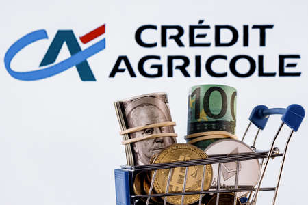 Kazan, Russia - Dec 16, 2021: Crypto and traditional currencies in shopping cart on background of Credit Agricole bank logoのeditorial素材