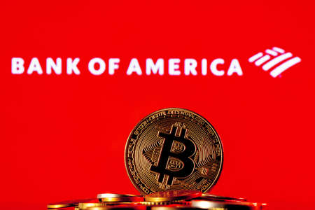 Kazan, Russia - Jan 09, 2022: Golden bitcoin in a pile of coins on the background of Bank of America logoのeditorial素材