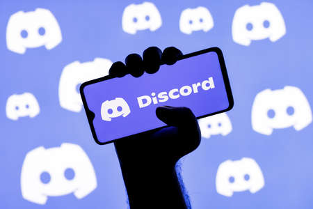 Kazan, Russia - Jan 20, 2022: Smartphone with the Discord social gaming platform on the screen in a clenched hand on the background of Discordのeditorial素材