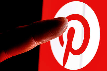 Kazan, Russia - Feb 09, 2022: The finger reaches for Pinterest social media service on smartphone...
