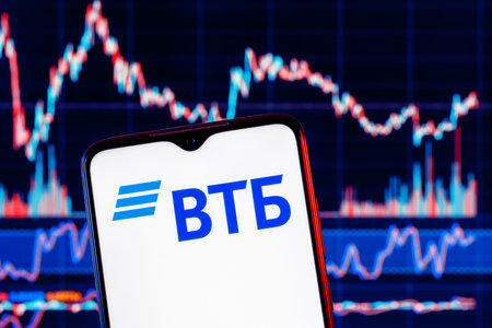 Kazan, Russia - Feb 23, 2022: Smartphone with VTB bank . VTB stock chart on background.のeditorial素材
