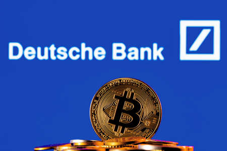 Kazan, Russia - Apr 04, 2022: Golden bitcoin in a pile of coins on the background of Deutsche bank logoのeditorial素材