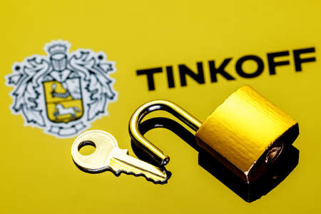 Kazan, Russia - Mar 06, 2022: An open security lock and key on background of Tinkoff bank logo in mirror reflectionのeditorial素材