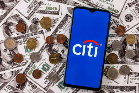 Kazan, Russia - Mar 11, 2022: Smartphone with Citigroup logo surrounded by variety of metal coins on background of dollar billsのeditorial素材