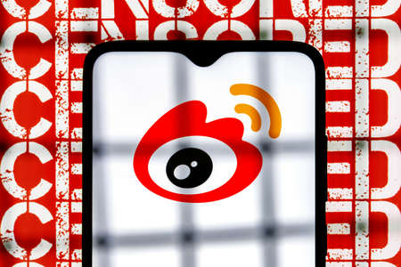 Kazan, Russia - Mar 10, 2022: Weibo chinese microblogging service logo on smartphone screen behind bars on background with inscription censored. The concept of Weibo censorship.のeditorial素材