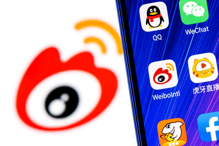 Kazan, Russia - Mar 10, 2022: The icon of the Weibo chinese microblogging service application among other applications on smartphone screen. On background is Weibo logo.のeditorial素材
