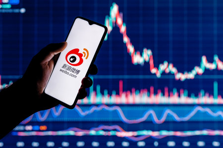 Kazan, Russia - Mar 10, 2022: Smartphone with Weibo chinese microblogging service logo on screen. Weibo stock chart on the background.のeditorial素材