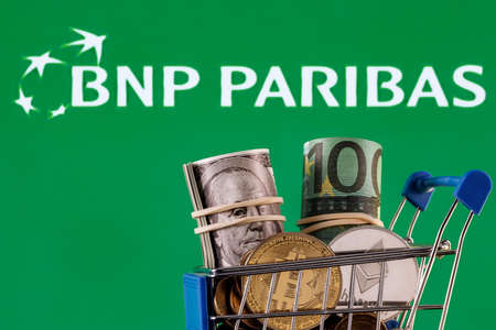 Kazan, Russia - Apr 27, 2022: Crypto and traditional currencies in shopping cart on background of BNP Paribas bank logoのeditorial素材