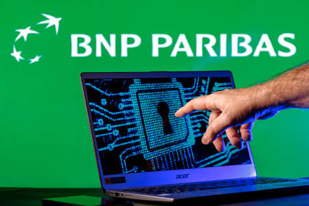 Kazan, Russia - Apr 27, 2022: Laptop with lock symbol on screen on background of BNP Paribas bank logo. Finger points to lock symbol. Concept of data hacking.のeditorial素材