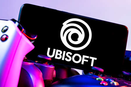 Kazan, Russia - Apr 15, 2022: Ubisoft is French video game company. Smartphone with Ubisoft logo on screen on pile of gamepads.のeditorial素材