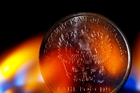 Close up of obverse of ruble coin with coat of arms of Russia on gas burner. The concept of Russia...