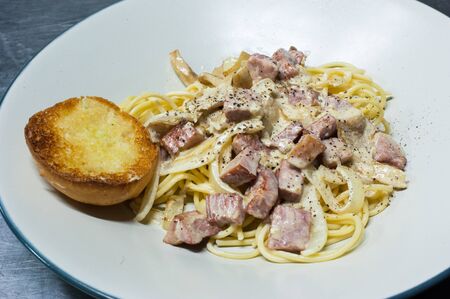Spaghetti white sauce with ham and garlic breadの写真素材