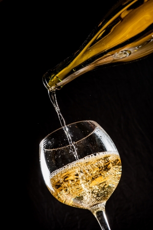 pouring white wine into a wineglass on tableの写真素材