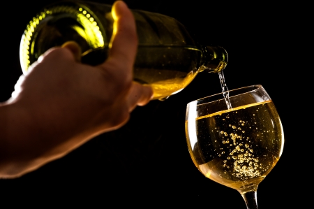 pouring white wine into a wineglass on tableの写真素材