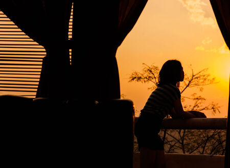 Girl in silhouette by sunset lightの写真素材