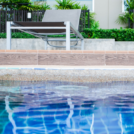 Relaxing pool chair by side of swimming poolの写真素材