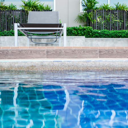 Relaxing pool chair by side of swimming poolの写真素材