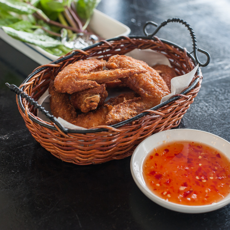 Fried chicken wings in basket with sauceの写真素材