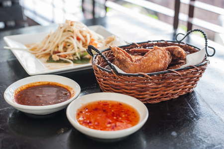 Fried chicken wings in basket with local sauce and Papaya spicy saladの写真素材