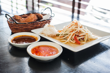 Papaya spicy salad named "Som Tum", Thai food with fried chicken wingsの写真素材