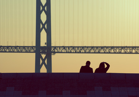 silhouette couple sitting together with bridge in pastel, vintage style