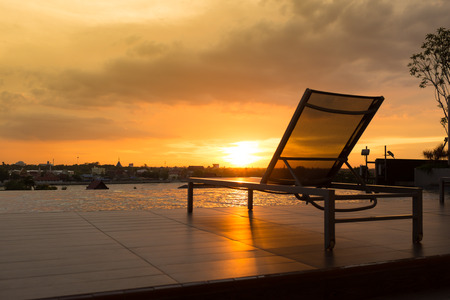Swimming pool chair by swimming pool with sunsetの写真素材