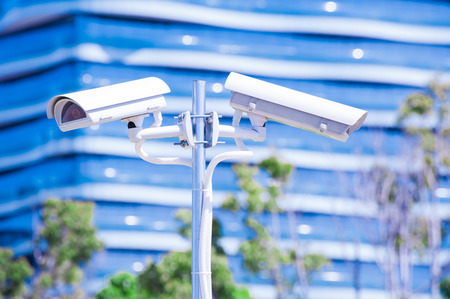 CCTV camera or surveillance operaiting with blue building in backgroundの写真素材