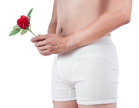 close up of man on white boxer underware  holding red rose isolate on white backgroundの写真素材