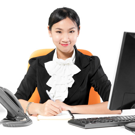Young pretty business woman taking note on working deskの写真素材