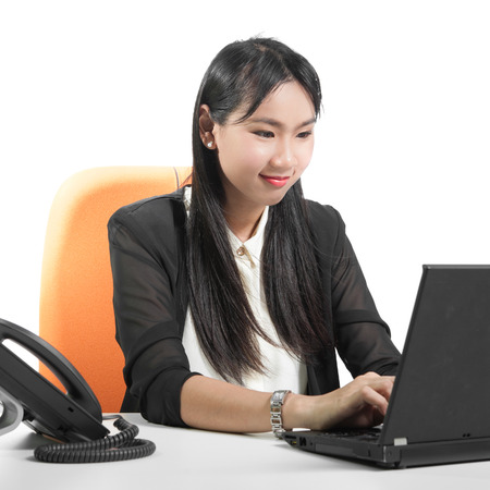 Young pretty business woman using laptop computer with phone on deskの写真素材