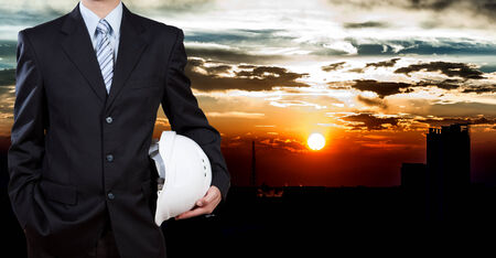 Businessman holding safety helmet with city backgroundの写真素材