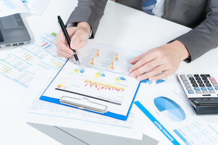 Businessman analyzing report on chart with laptop and calculatorの写真素材