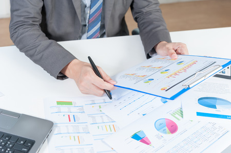 Businessman analyzing report on chart with laptopの写真素材