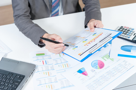 Businessman analyzing report on chart with laptop and calculatorの写真素材