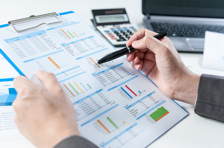 Businessman analyzing report on chart with laptop and calculatorの写真素材