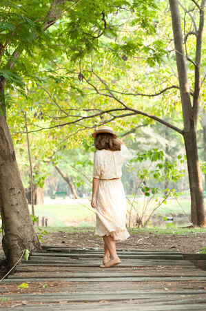 beautiful young woman walk in park hold hat against wind blowの写真素材