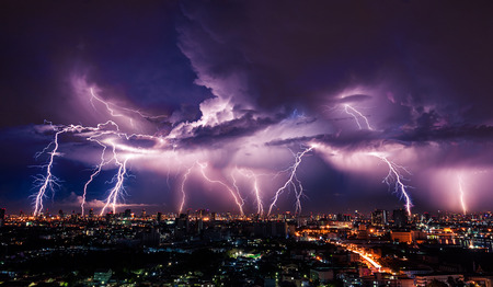 Lightning storm over city in purple lightの写真素材