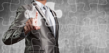 Businessman using tablet showing jigsaw piece, business decision conceptの写真素材