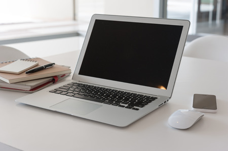 Laptop with book and smartphone on work deskの写真素材
